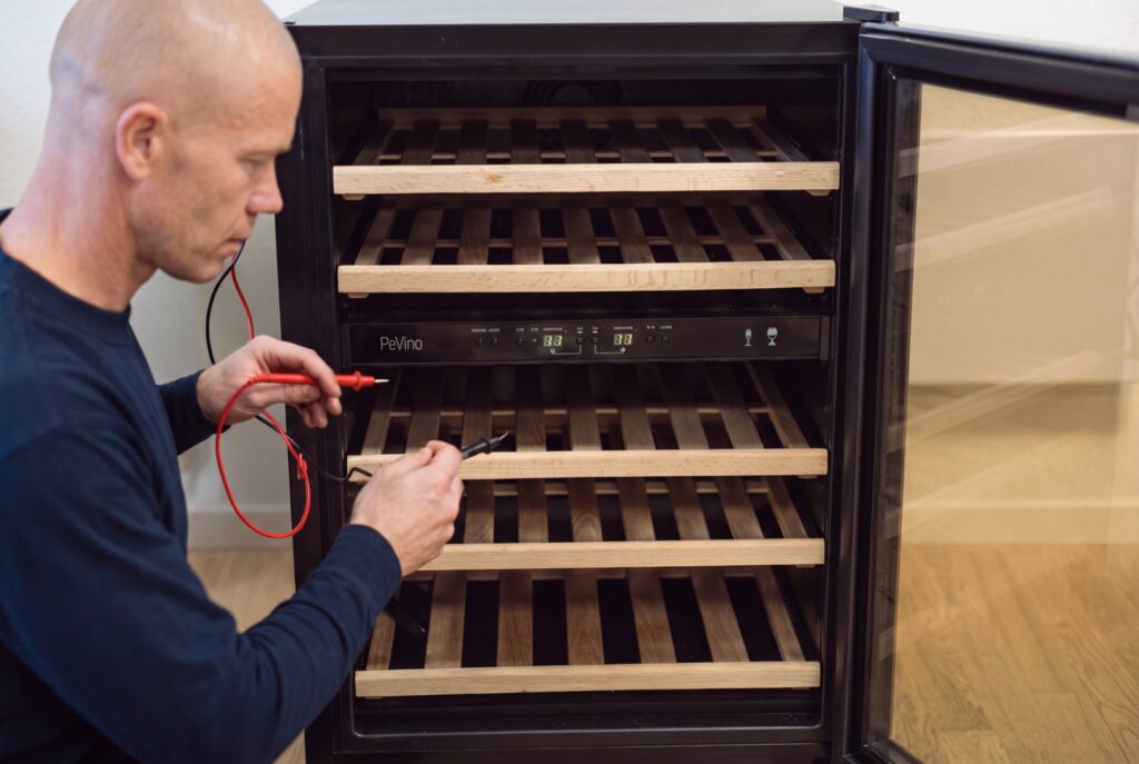 Montør måler med multimeter på betjeningspanelet under fejlsøgning af en hvidevare.